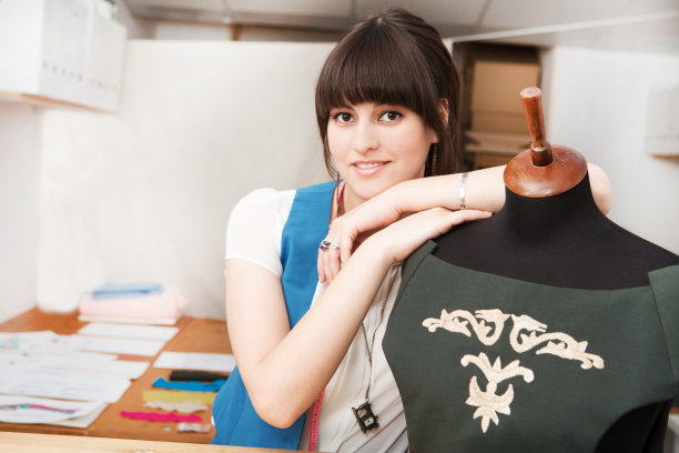年轻的女时装设计师在她的工作室工作服装上的人体模型。