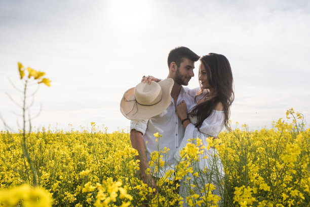 一对年轻的情侣在一片黄色的毛茛花丛中调情。