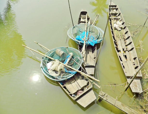 运河里有三艘古代木船,船上有捕鱼工具.