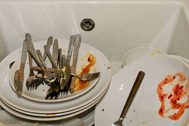厨房水槽里的脏盘子和刀叉。