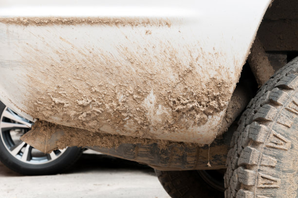 极其肮脏的白色公路4x4汽车与大量的泥土，泥和灰尘从后方驾驶通过潮湿的地面和自然近距离