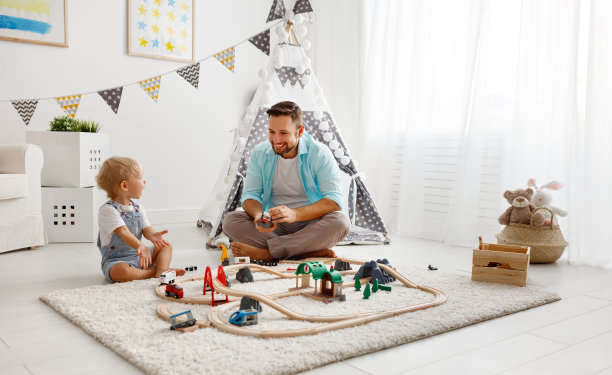 快乐的家庭，爸爸和孩子在玩具铁路玩在游戏室