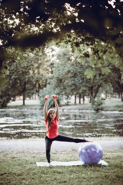 女运动员在大自然中用健身球练习瑜伽普拉提
