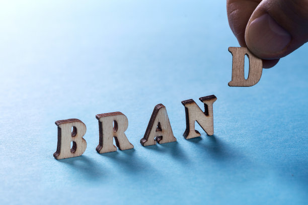 bramd是在一个蓝色背景上的木制字母,一个男人的手拿着一个字母d.