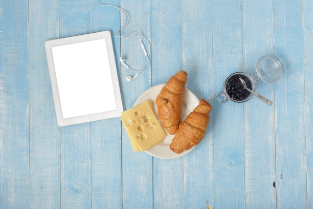 早餐桌上有白色的药片，羊角面包，果酱，奶酪和咖啡在家庭厨房，俯视图