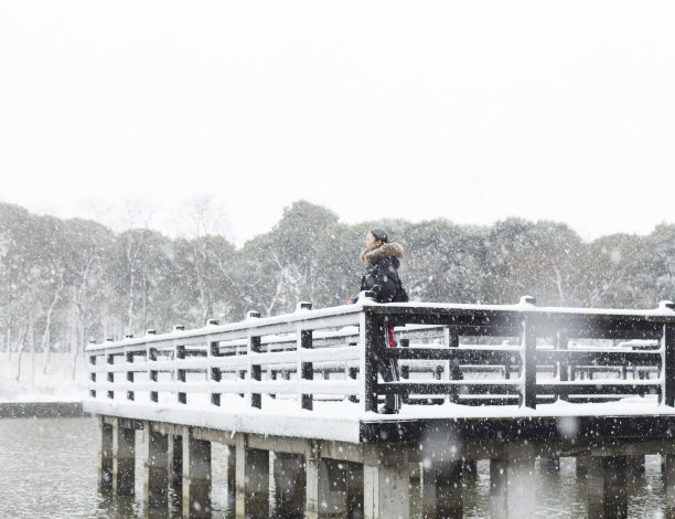 一个女人站在白雪覆盖的木桥上的宁静景象