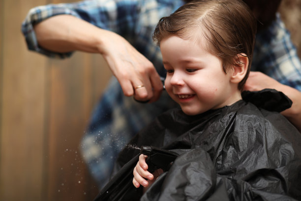 一个小男孩被美发师欢快的情绪迷住了