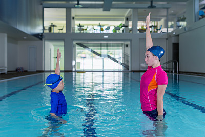 游泳课。可爱的小男孩和游泳教练一起学游泳