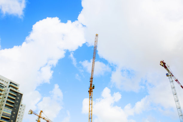 建筑吊车塔以蓝天为背景。施工现场起重机和建筑施工进度。解除水龙头。
