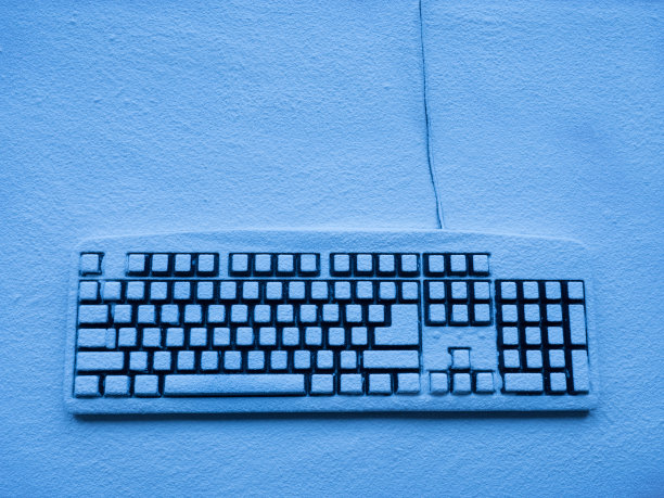 电脑键盘上覆盖着雪，并被蓝色的霓虹灯照亮