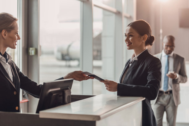 微笑的年轻女商人在机场办理登机手续时将护照和机票交给工作人员