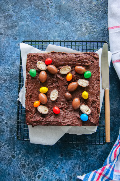 用奶油巧克力蛋装饰的铁丝架上的黑巧克力布朗尼.蓝石头背景.