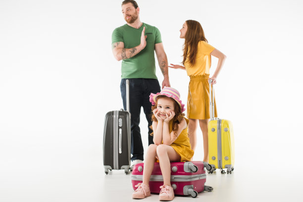 心烦意乱的小孩坐在行李箱上，而父母则在争论白色，旅行的概念