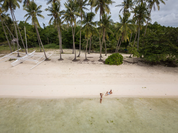 无人机拍摄的年轻夫妇在热带海滩上放松的鸟瞰图