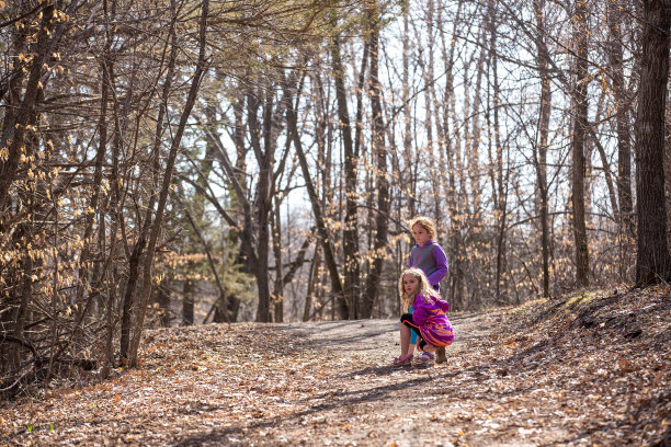 两个小女孩停在树林里的小径上