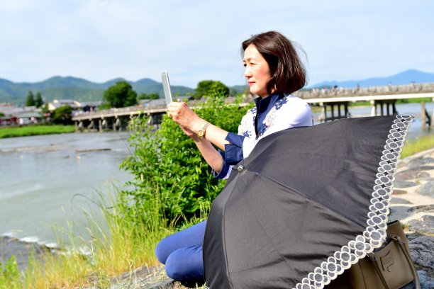 一名日本女子在京都岚山河岸上放松、自拍