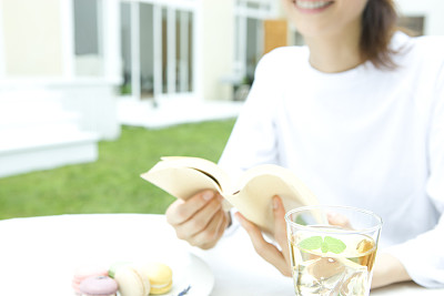 年轻女子读着一本书，配着甜点和香草茶