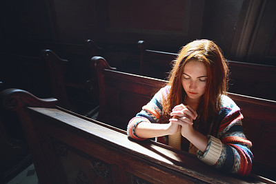 年轻女子在教堂祈祷
