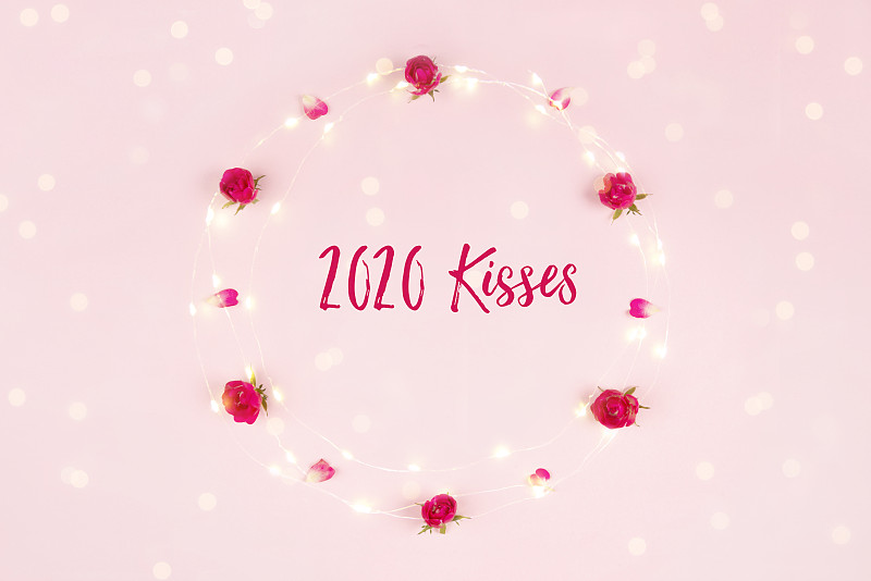 Frame,of,roses,and,rose,petals,with,fairy,lights,on,a,pink,background,with,the,inscription,?2020,Kisses“