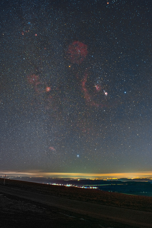 Winter,night,sky,including,Barnard’s,Loop,,the,Orion,Nebula,,the,Flame,Nebula,,the,Rosette,Nebula,,and,the,bright,star,Sirius,photographed,from,the,summit,of,the,mountain,Witthoh,in,Germany.