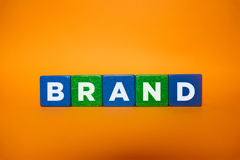 Wood,cube,block,with,word,“BRAND”,on,orange,background.,Brand,building,for,success,concept