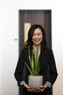 一个日本女人在办公室走廊上种着绿色植物