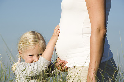 小女孩抚摸着怀孕的母亲的肚子