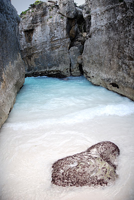岩石海滩，蓝色的水和白色的沙子