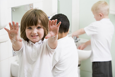 小女孩在一所小学的浴室里展示她涂了肥皂的手