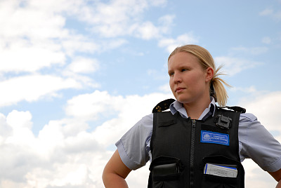 一个穿着警察背心的女人站在天空前