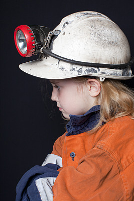 年轻的女孩戴着矿工安全帽和安全服