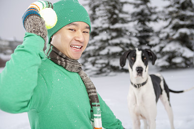 冬季微笑的亚洲男子与狗玩接球