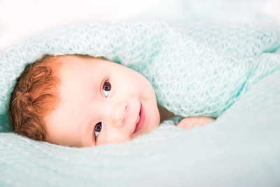 毯子下微笑的婴儿
