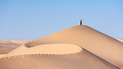 女游客站在撒哈拉沙漠的沙丘顶部