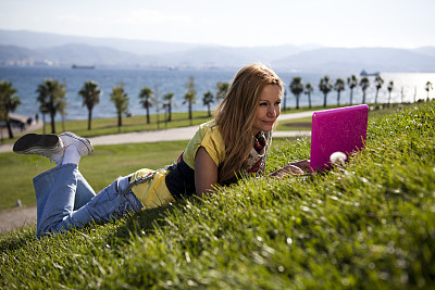年轻女子在公园里用笔记本电脑