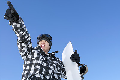 兴奋的男性滑雪板指向蓝色的天空