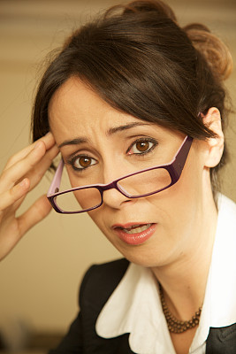 戴眼镜的女人在工作中感到疲惫