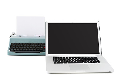 一台老式打字机前放着一台现代笔记本电脑