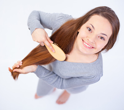 一位年轻女子微笑着梳着头发。