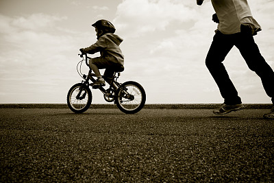 父亲追着一个学骑车的年轻人