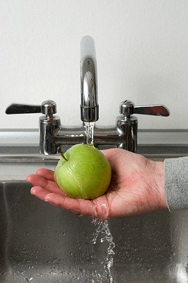用水龙头冲洗一个青苹果的健康生活方式