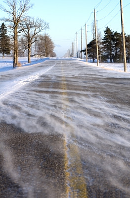 空旷的道路上覆盖着积雪，两旁是光秃秃的树木