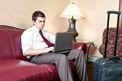 年轻的商人在酒店大厅用笔记本电脑工作