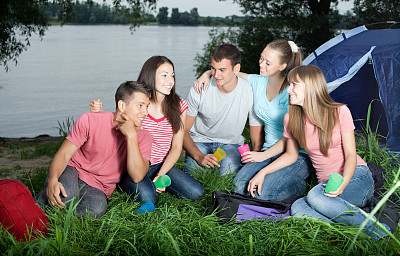 一群青少年坐在营地里聊天。