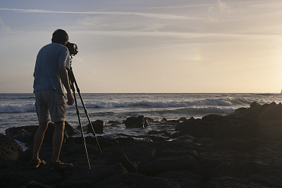 男子拍摄夏威夷太平洋日落使用三脚架，背面视图
