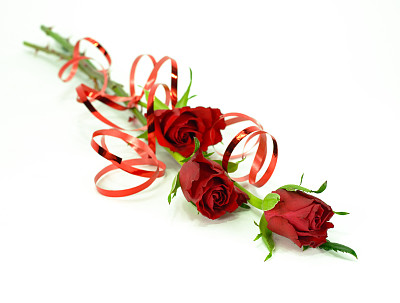 三个深红色的玫瑰茎孤立在白色上，带丝带