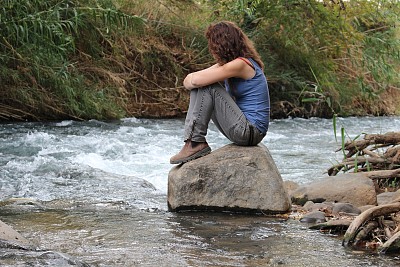 一个年轻的徒步旅行者坐在一块岩石上