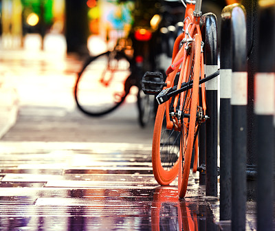 瑞德把自行车停在城市的人行道上。下雨的晚上。