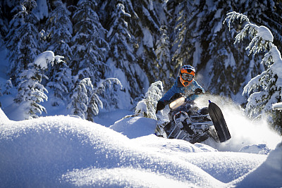 机动雪上摩托车在松树下的斜坡上滑行的动作镜头