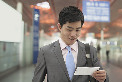 中国北京，一位年轻的商人正在机场看机票